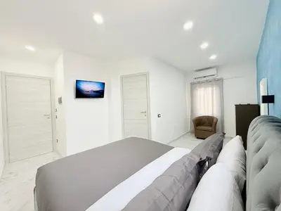 a white bedroom with a large bed and a chair at ROME PLACE guest house in Rome