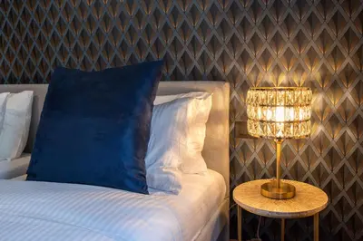 a bed with a blue pillow and a table with a lamp at Confort Collection Trastevere in Rome