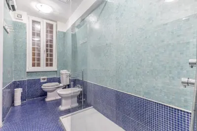 a bathroom with a toilet and a blue tiled wall at Casa Iside in Rome