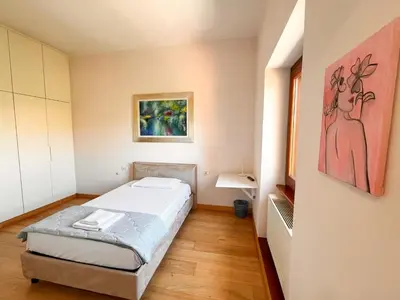 a small room with a bed and a painting on the wall at Divine View Apartment in Rome