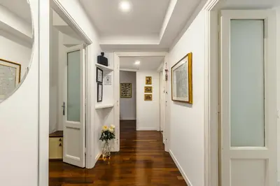 a hallway with white walls and wood floors and a vase of flowers at Br1tannia 36 in Rome