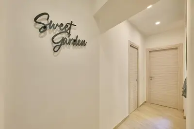a white hallway with a sign that reads sweet garden on the wall at SweetgardenTrastevere in Rome