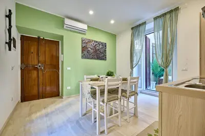 a kitchen with green walls and a table and chairs at SweetgardenTrastevere in Rome