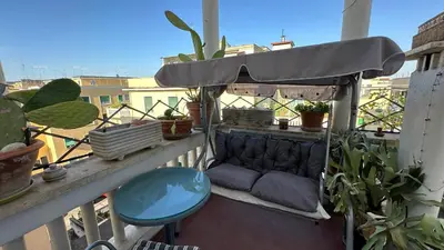 a couch on a balcony with plants and an umbrella at The attic in Rome