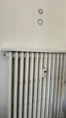 a radiator against a white wall with a light at The attic in Rome