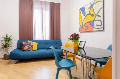 a living room with a blue couch and a glass table at Oliviero - Colosseo Apartment with Terrace in Rome