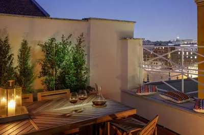 a balcony with a wooden table and glasses of wine at Daplace - Costanza Apartment in Rome