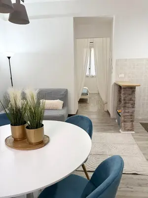 a living room with a white table and blue chairs at VOLUPTA' S HOUSE in Rome MANZONI - COLOSSEO in Rome