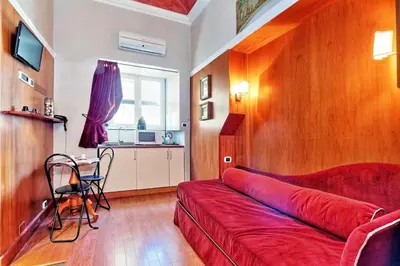 a living room with a red couch and a table at Colosseum Studio in Rome