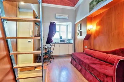 a living room with a red couch and a ladder at Colosseum Studio in Rome