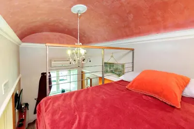 a bedroom with a red bed and a chandelier at Colosseum Studio in Rome