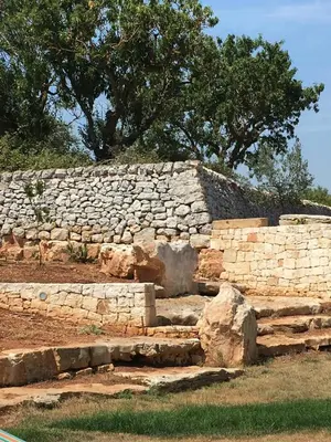 a stone retaining wall with trees in the background at Trullo Amato with exclusive pool in Rome