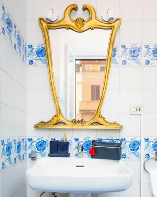 a bathroom with blue and white tiles and a mirror at Luxury house Empire 96 in Rome