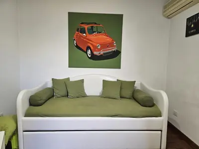 a couch in a room with a picture of a car at Be Your Home - Spritz Apartment in Rome