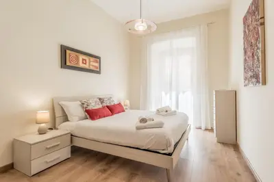 a bedroom with a bed with white sheets and red pillows at Elegant flat in front of Vatican museum in Rome