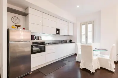 a kitchen with white cabinets and a stainless steel refrigerator at The Vatican Rest, Elegant Apt Nerby the Basilica in Rome