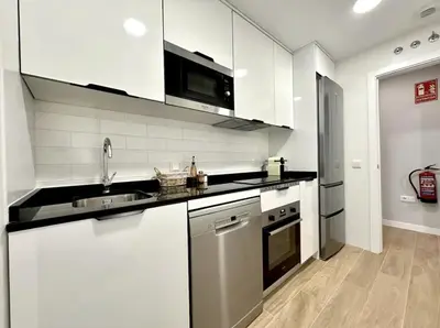 a kitchen with white cabinets and a sink and a refrigerator at Il CIGNO in Rome
