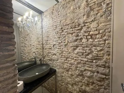 a bathroom with a sink and a stone wall at Colosseum loft in Rome