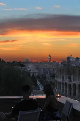 a man and a woman sitting on a balcony watching the sunset at Hexa in Rome