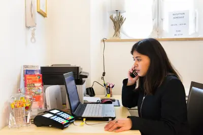 a woman talking on a phone at a desk with a laptop at Domus Trevi in Rome