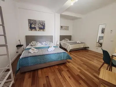a bedroom with two beds and a wooden floor at Via Lattea Vatican Apartment - Family friendly in Rome