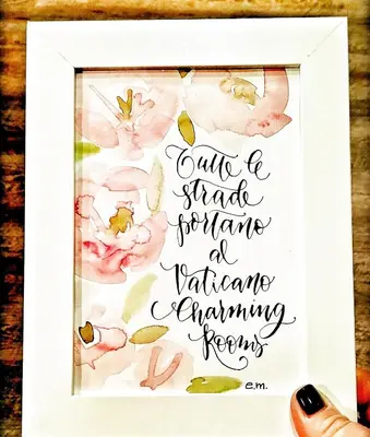 a framed picture of aigraphy poem with pink flowers at Vaticano Charming Rooms in Rome