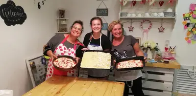 three women holding up two pans of food at Vaticano Charming Rooms in Rome
