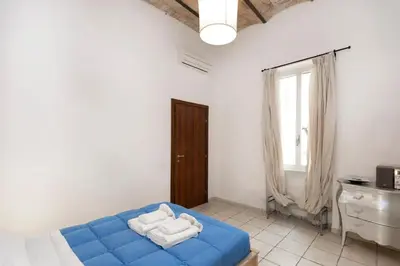 a bedroom with a blue bed and a window at San Pietro Terrace Apartment in Rome