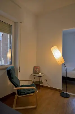 a room with a chair and a lamp and a table at Appiano Garden Apartment in Rome