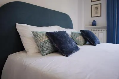 a white bed with four pillows on it at Dolce Roma Apartment in Rome