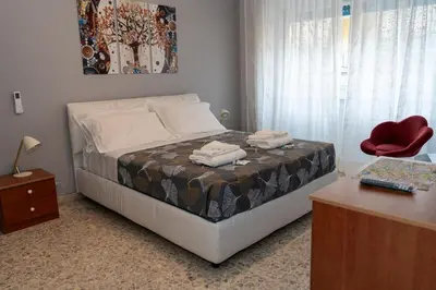 a bedroom with a bed with a red chair and a desk at La casa di Gegè Appio Caffarella in Rome