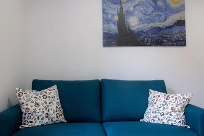 a blue couch with two pillows sitting under a painting at Aunt's Vatican Home in Rome