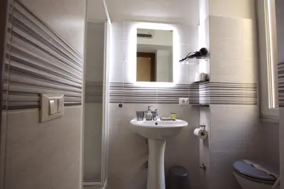 a bathroom with a sink and a mirror and a toilet at Ottaviano 2BR Holiday House in Rome