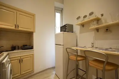 a kitchen with two bar stools and a white refrigerator at Ottaviano 2BR Holiday House in Rome