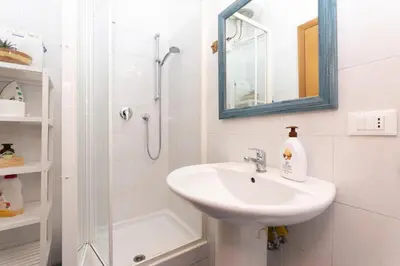 a white bathroom with a sink and a shower at 10 Min Città del Vaticano-Stadio olimpico Lucia Apartment 1BDR in Rome