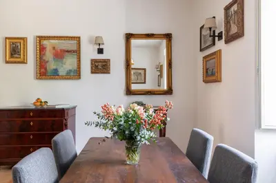 a vase of flowers on a wooden table with chairs at iFlat Charming & Spacious Flat in Trastevere in Rome