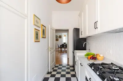 a kitchen with white cabinets and a black and white checkered floor at iFlat Charming & Spacious Flat in Trastevere in Rome