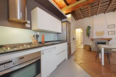 a kitchen with white cabinets and a stove top oven at Trastevere Historic Loft by Luxury Getaways in Rome