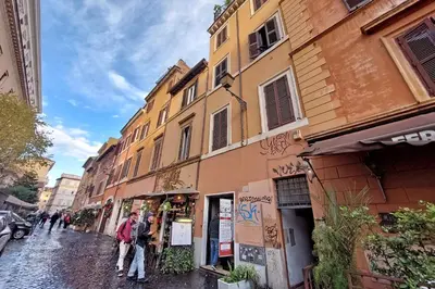 a group of people walking down a street next to buildings at Trastevere Historic Loft by Luxury Getaways in Rome