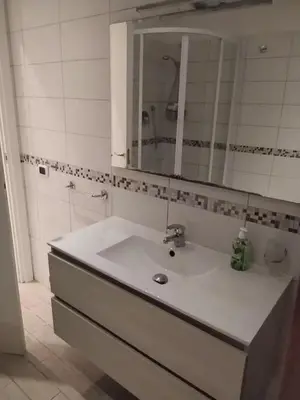 a white bathroom with a sink and a mirror at Garbatella seminterrato in Rome