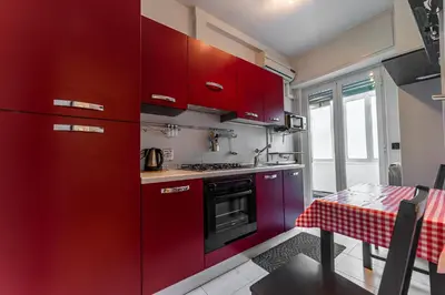 a kitchen with red cabinets and a table with a table cloth at Desiré Flat - Vatican City - Metro Cipro and WiFi in Rome