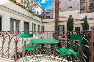 a green table and two chairs on a balcony at Vittorio Emanuele Grand Apartment in Rome