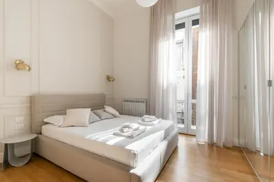 a white bedroom with a large bed and a window at Vittorio Emanuele Grand Apartment in Rome