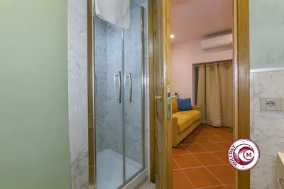 a glass shower in a bathroom with a yellow couch at C M Barberini Vacation in Rome