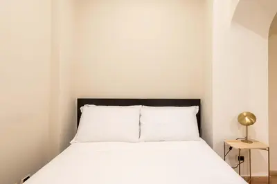 a bedroom with a bed with white sheets and a lamp at Loft nel Cuore della Capitale in Rome