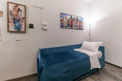 a room with a blue bed and paintings on the wall at Francesca Suite - Metro Basilica San Paolo in Rome