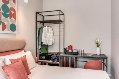 a bedroom with a bed and a desk with a mirror at Parioli Cube Hotel in Rome