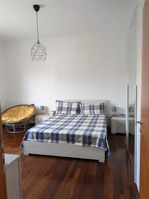 a bedroom with a bed with a blue and white plaid blanket at Spacious and silent two-bedroom apartment in Tor Marancia in Rome