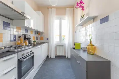 a large kitchen with white cabinets and a window at Daplace - Cosima Apartment III in Rome