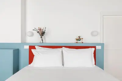 a bed with a blue and red headboard with white pillows at Off in Rome